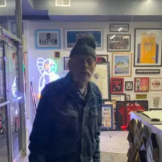 Man in dark cap and jacket at doorway celebrating Hasbrouck Heights National William Day.