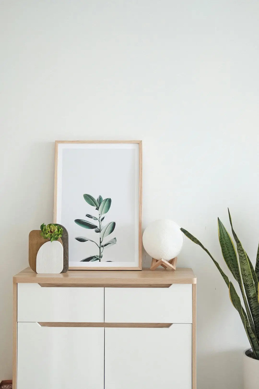 White cabinet with wooden trim showcasing minimalist decor and canvas art prints.