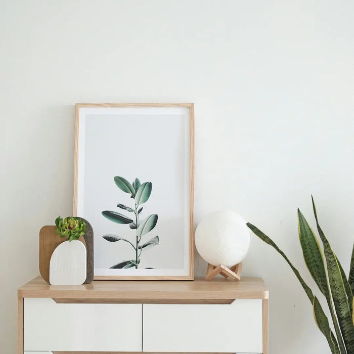 White cabinet with wooden trim showcasing minimalist decor and canvas art prints.