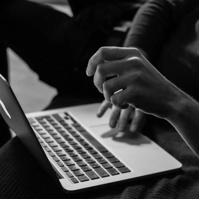 Hands typing on a laptop for researching online stores for wall decor and picture framing