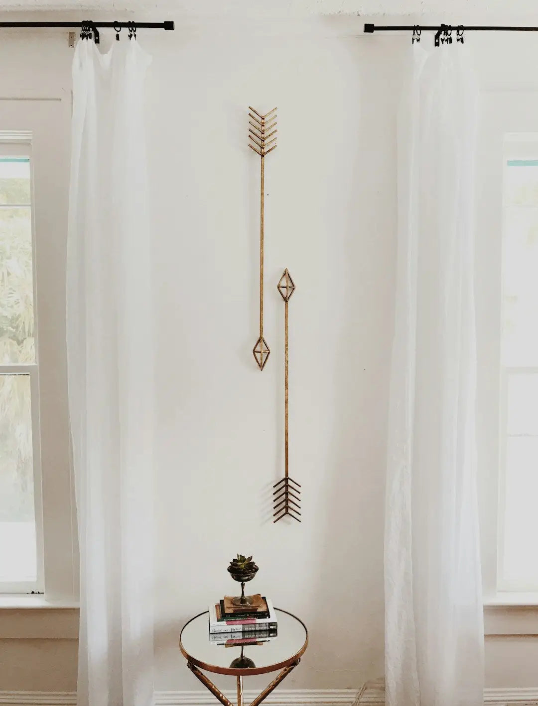 Decorative metal arrow with geometric shapes as modern canvas wall decor on white wall.