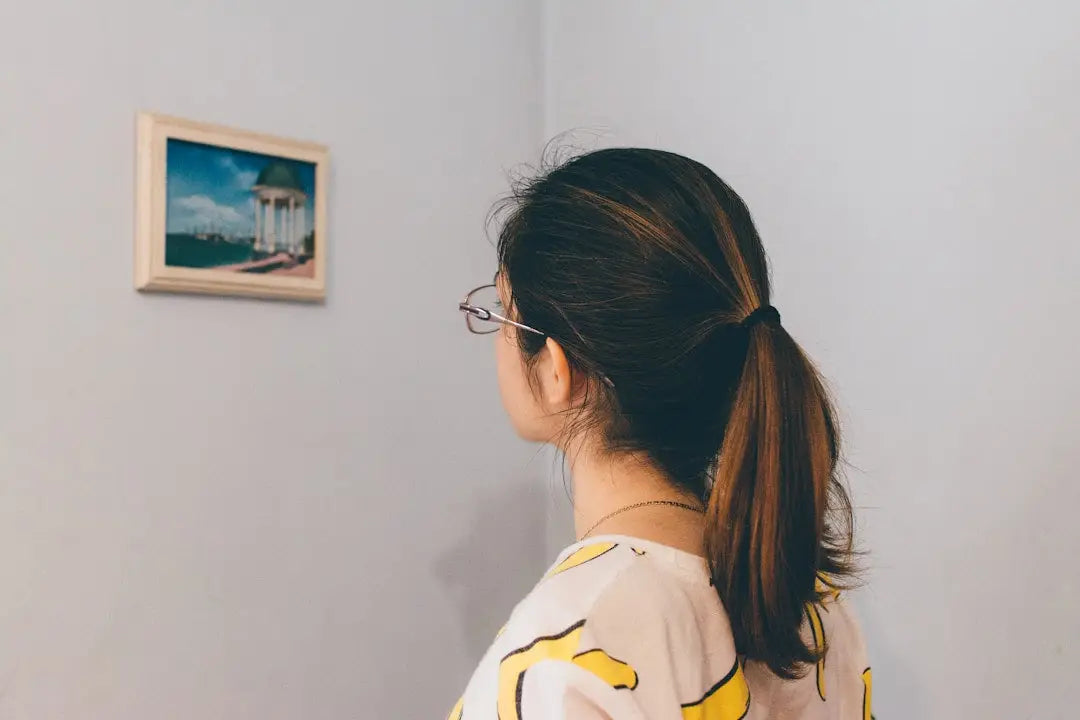 Person with dark ponytail and glasses designing a gallery wall in modern memory style