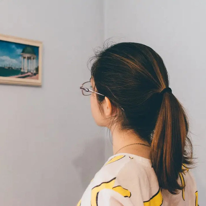 Person with dark ponytail and glasses designing a gallery wall in modern memory style