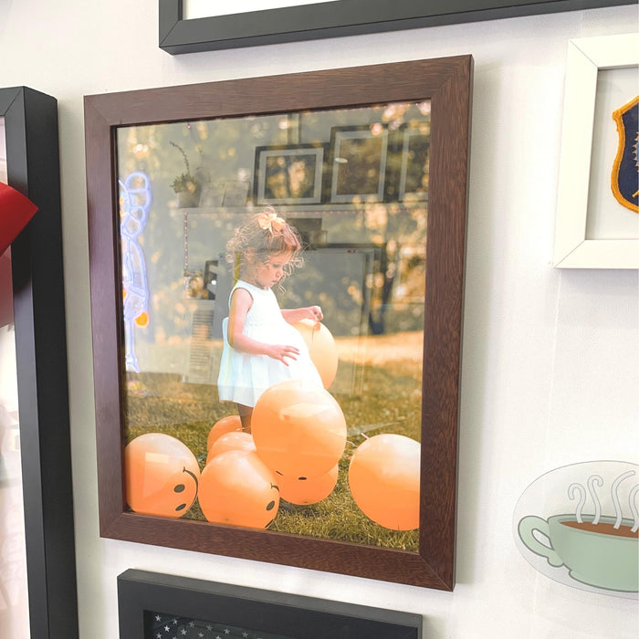 Framed photograph of a child among orange pumpkins in a 42x46 picture frame