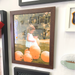 Framed photograph of a child with orange balloons in a brown wood picture frame wall hanging