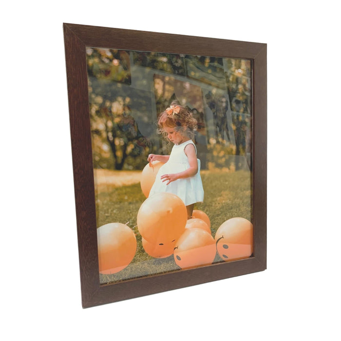 Framed photograph of a child on orange balloons in a brown wood picture frame wall hanging